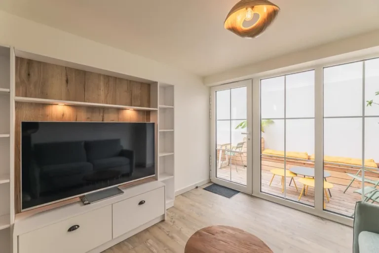 Meuble TV et bibliothèque sur mesure face à une baie ouverte sur la terrasse – T2AE, Louviers